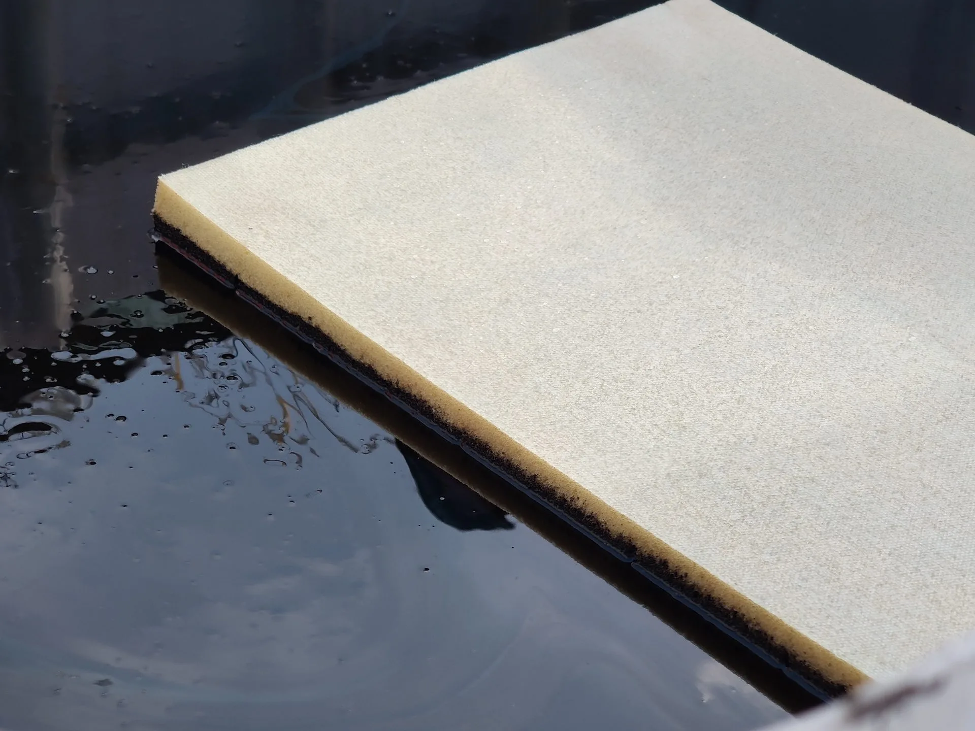 FoamFlex pad floating on oil in an IBC tank during an absorbent demonstration