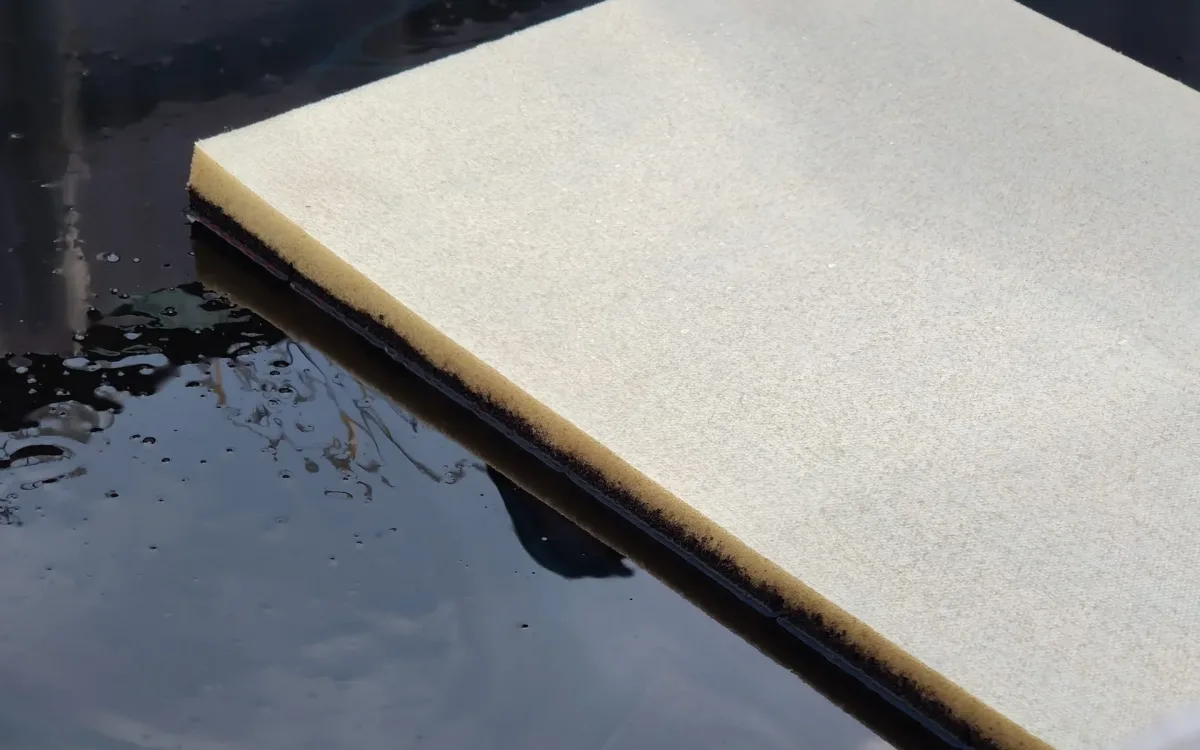 FoamFlex pad floating on oil in an IBC tank during an absorbent demonstration