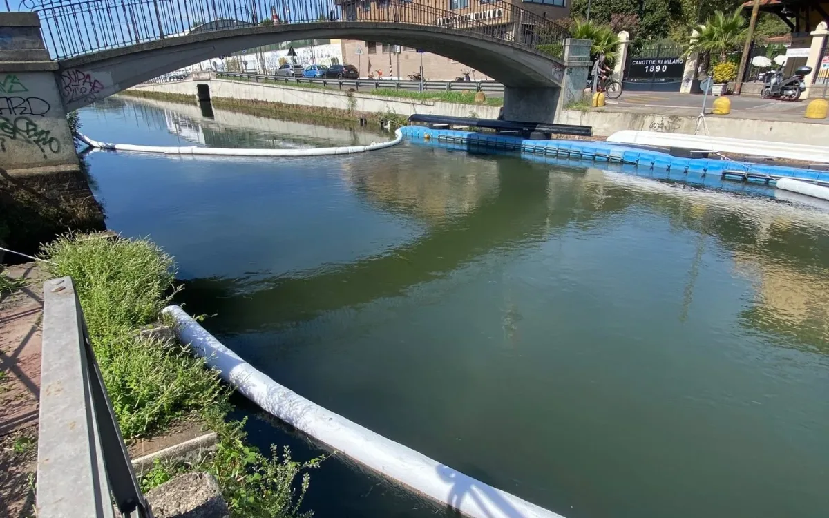 White absorbent line across a Milan canal near a footbridge