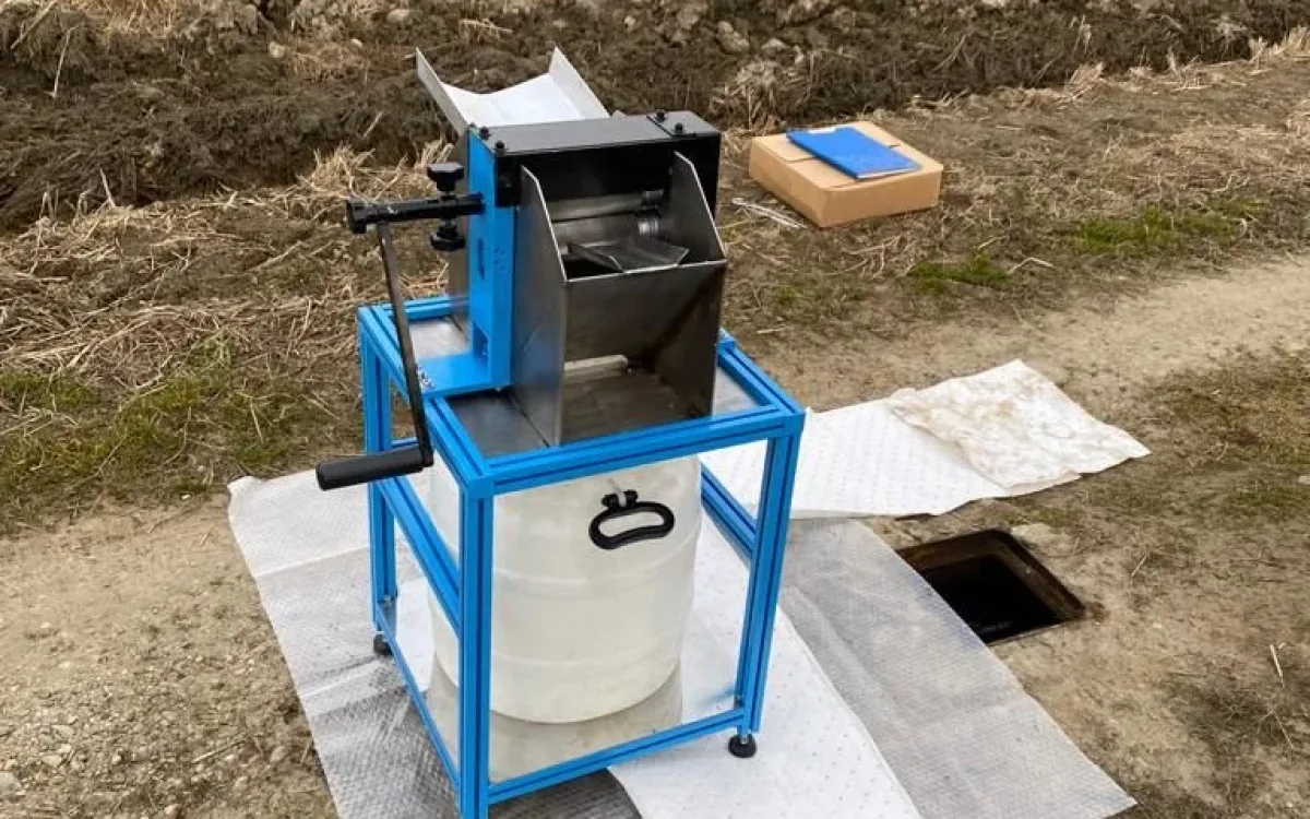 Wringing unit with collection container placed next to a piezometer cover in an open field