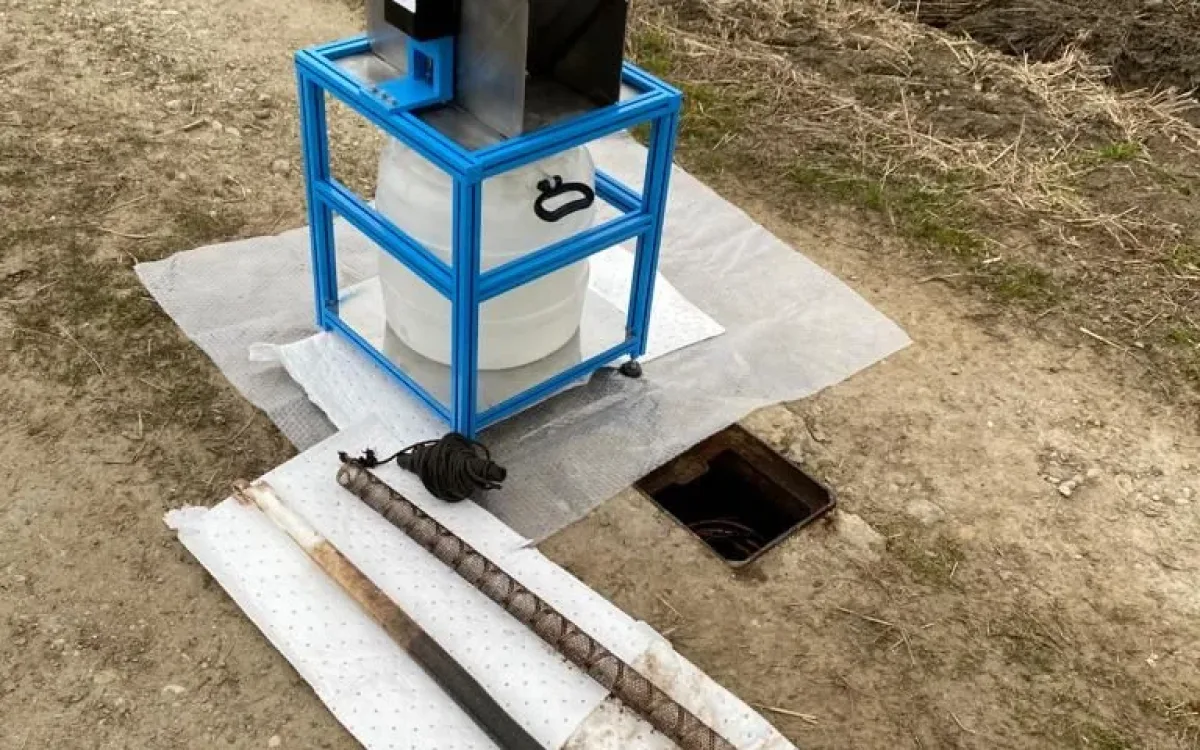 Wringing unit on a blue frame in the field next to the absorbent sock and cage laid on absorbent sheets