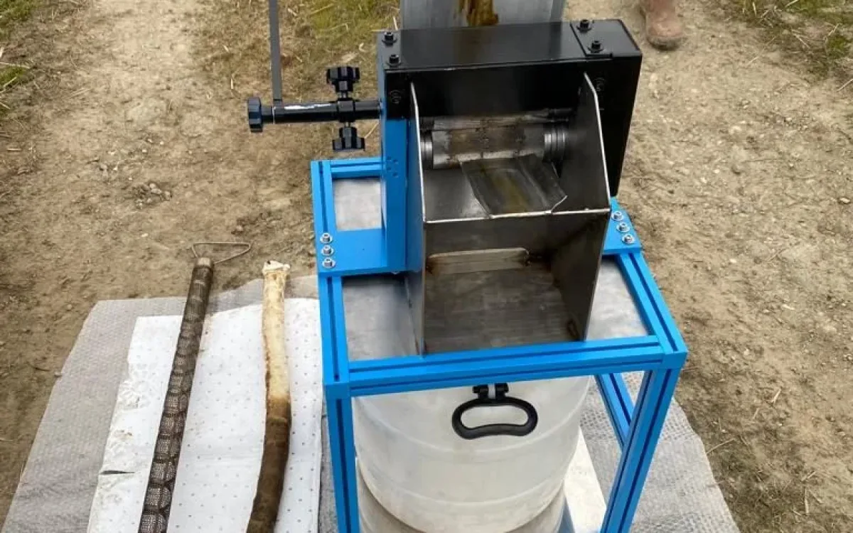 Wringing unit with sock being fed through, container underneath and absorbent mat on the ground