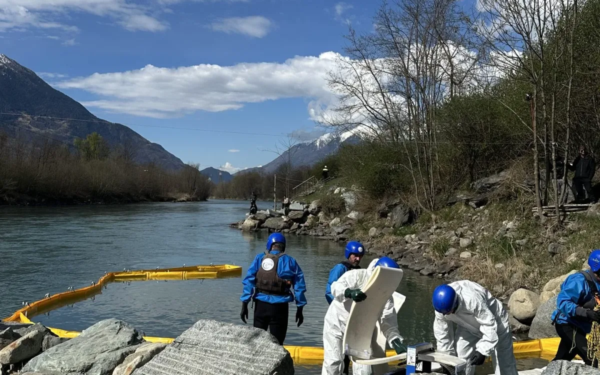 Operators at the water edge with a yellow boom stretched across the river